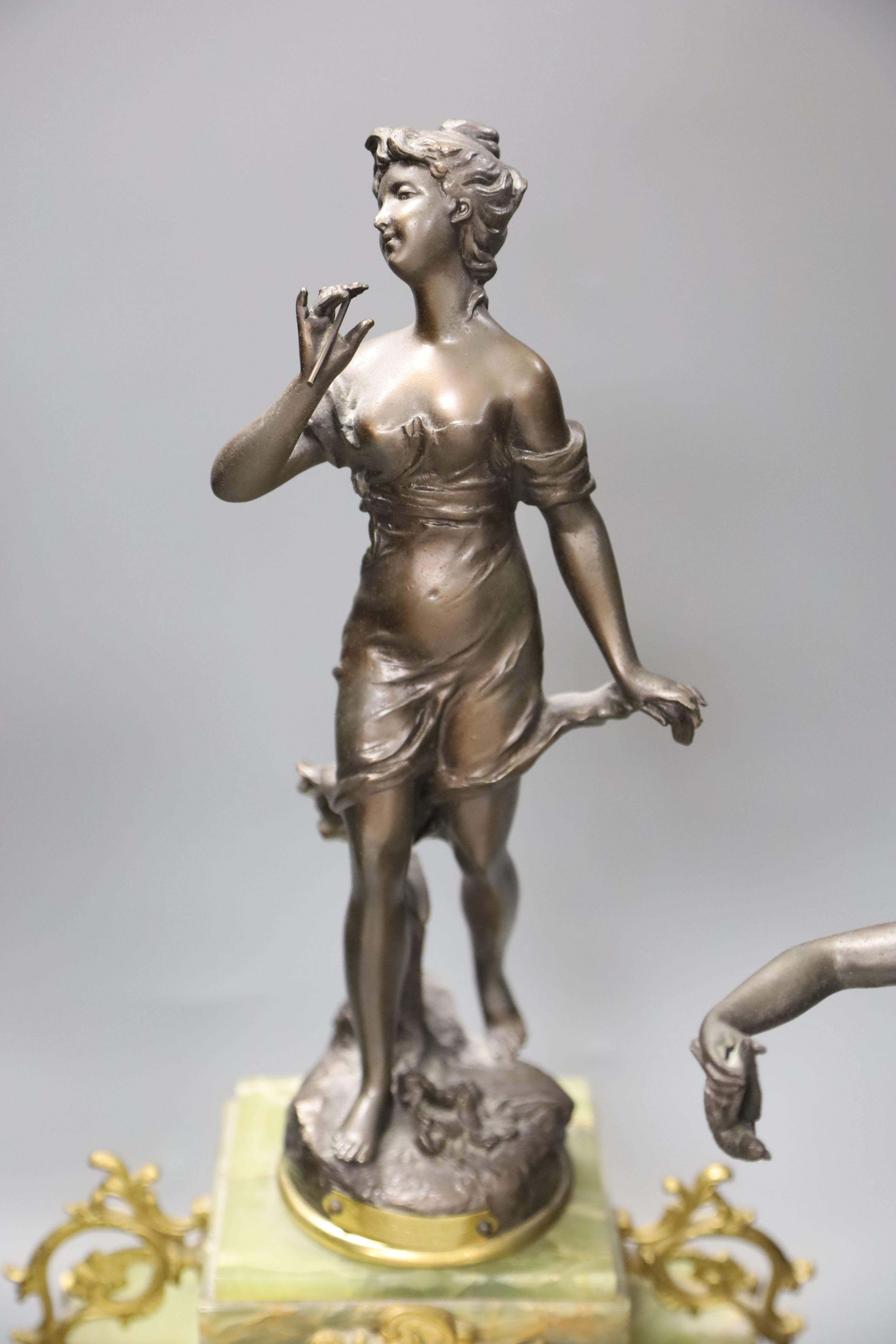 A French onyx and spelter figural clock garniture after Ferrand, plaques read Improvisateur Prisonniere and Sensitive, height 50cm